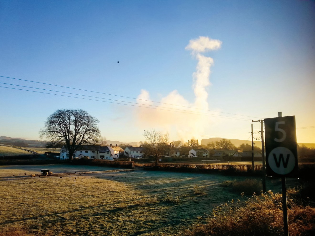 Through the train window, the Burneside paper mill makes cloud for the morning sky