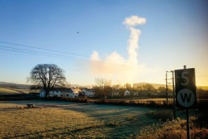 Through the train window, the Burneside paper mill makes cloud for the morning sky